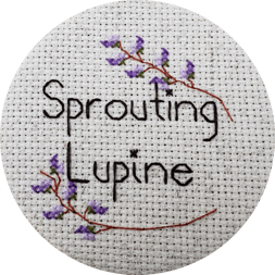 A stitched logo with the words "Sprouting Lupine" surrounded by purple lupine flowers